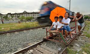 A train passing a 'trolley' - a makeshift rail cart made with wood or bamboo - in Manila, the Philippines.