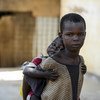 一个小孩背着他的妹妹。这两个孩子都住在南苏丹阿维尔街道上。儿基会/Rich