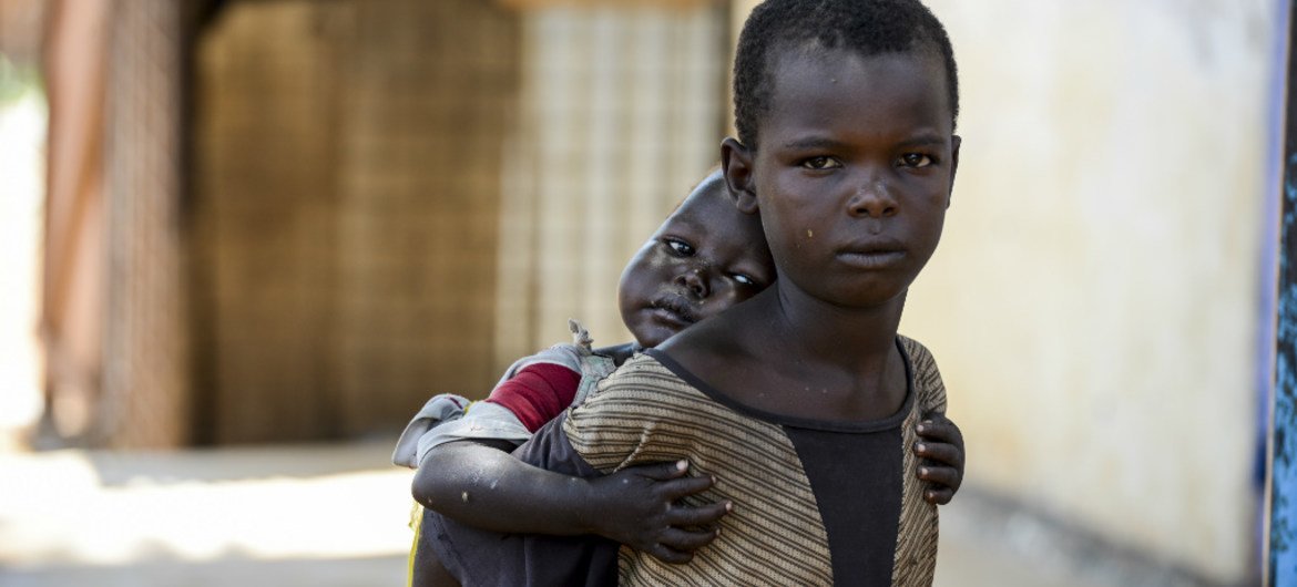 A child carries his younger sister on his back. Both children are living on the street in Aweil, South Sudan. UNICEF/Rich