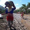 A woman and a child walk with their belongings along a road destroyed by Tropical Storm Tembin in Munai muncipality, Lanao del Norte, north Mindanao, the Philippines.