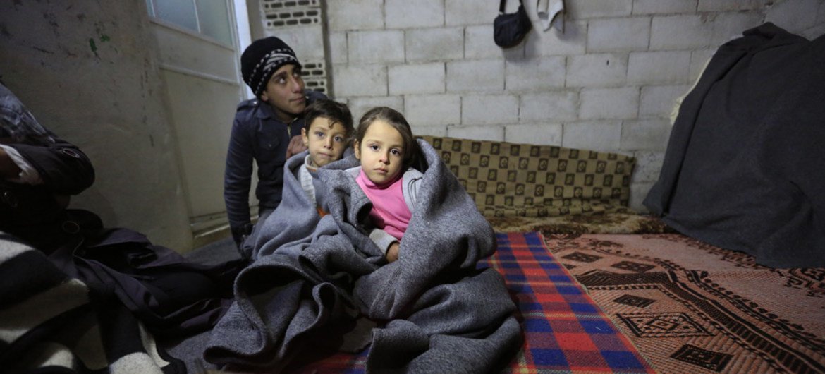 Сирийская семья  пытается укрыться от холода в  недостроенном  здании  в  одном из районов в Хомсе. Фото ЮНИСЕФ/Санадики