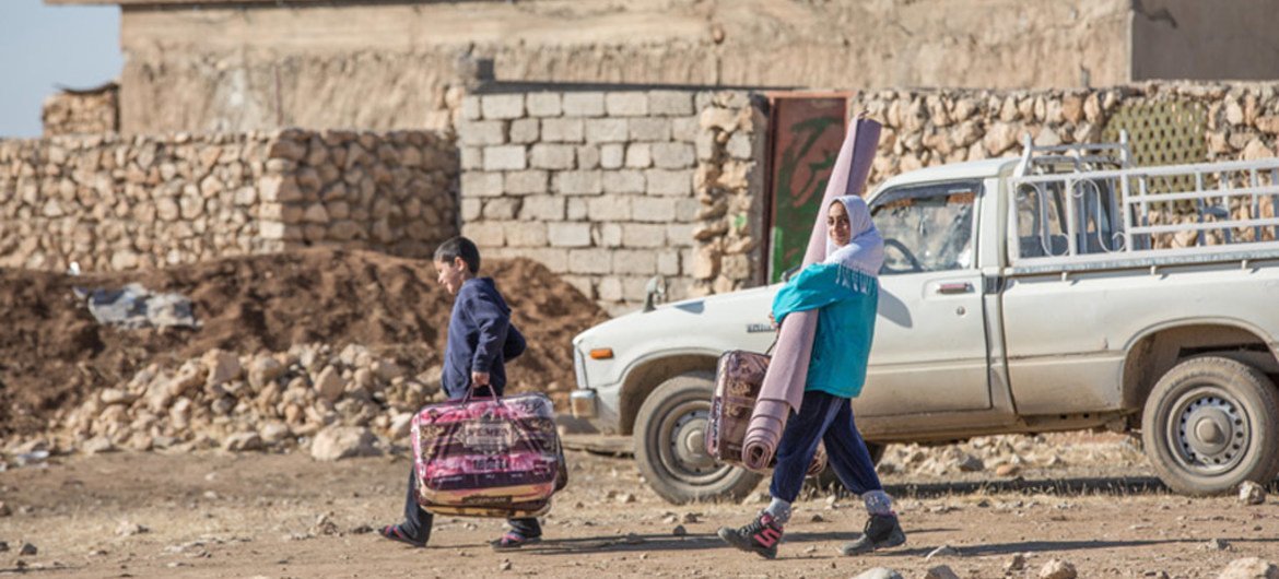 Iraqi returnee family in the village of Wana, west of the city of Mosul, carry away relief kit supplied by the UN International Organization for Migration (IOM).
