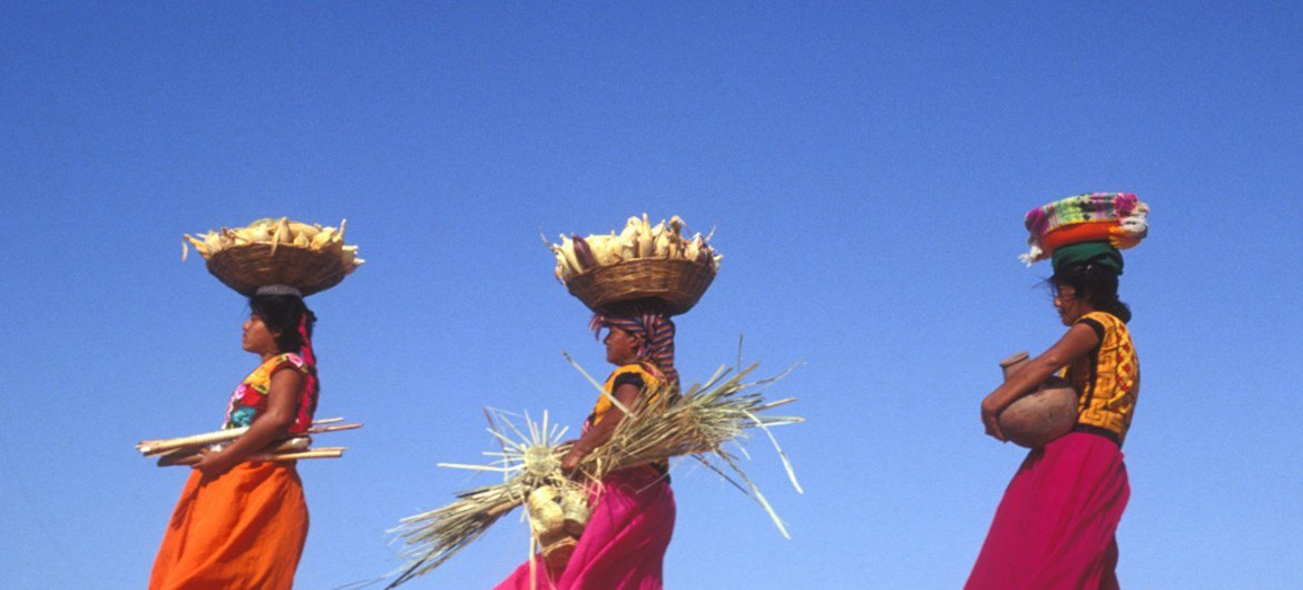 Mulheres carregam cestos com milho no México 