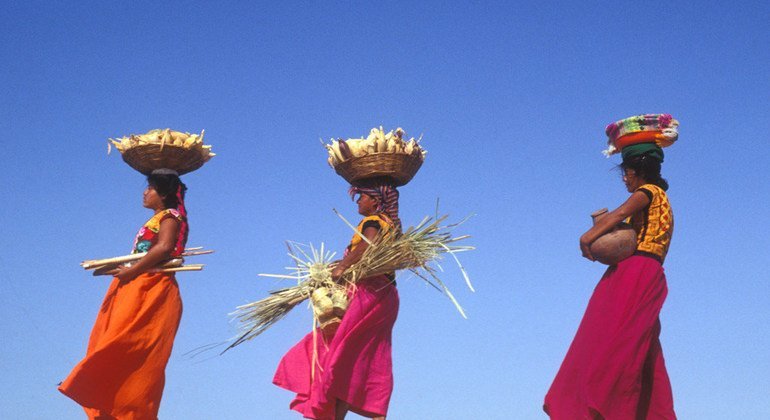 Mulheres carregam cestos com milho no México 