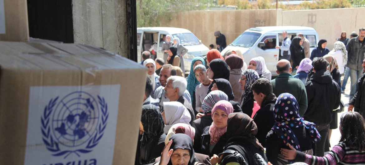 Beneficiaries queue for food assistance at the UNRWA distribution centre in Sahnaya, Damascus in Syria.