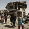 Mossoul, Iraq : des femmes et des enfants marchent à travers les décombres de bâtiments et des véhicules détruits lors d’intenses combats alors qu’ils fuient vers des zones sûres.