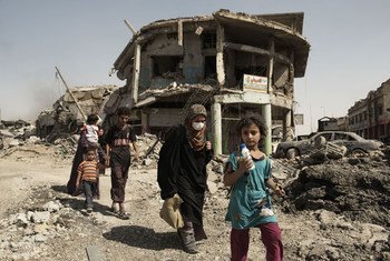 Mulheres e crianças andam em meio à destruição em Mossul, no Iraque