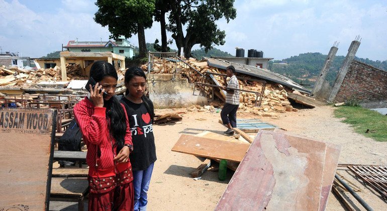 Две девочки  разговаривают с психологом  по мобильному телефону в отдаленной сельской местности в Непале. 