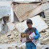Un enfant porte des manuels distribués par des volontaires de l'UNICEF à la suite d'une séance d'information sur les engins non explosés à Alep, en Syrie. Photo UNICEF/Al-Issa