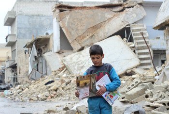 Un enfant porte des manuels distribués par des volontaires de l'UNICEF à la suite d'une séance d'information sur les engins non explosés à Alep, en Syrie. Photo UNICEF/Al-Issa