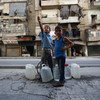 A 9-year-old boy and his brother, 6, wait for their turn to fill the empty jerry cans from a local water well in eastern Aleppo, in Syria.