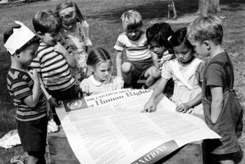 Un grupo de niños lee la Declaración Universal de los Derechos Humanos en un jardín de niños.