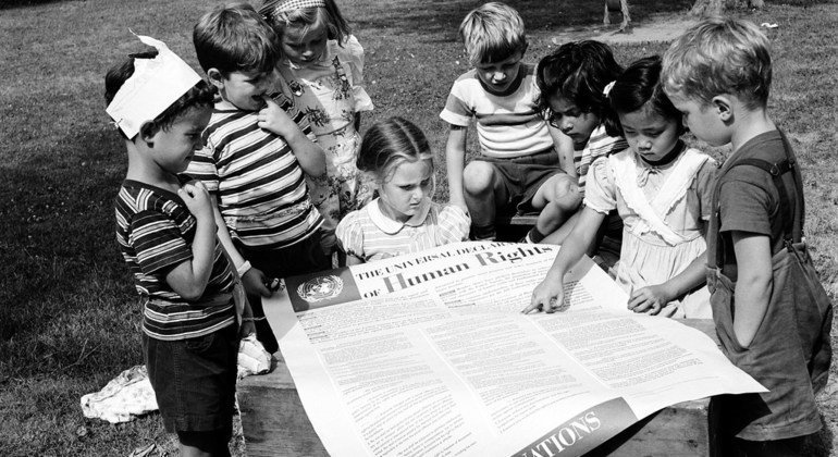 Young children read the Universal Declaration of Human Rights at a playground. (Archive)