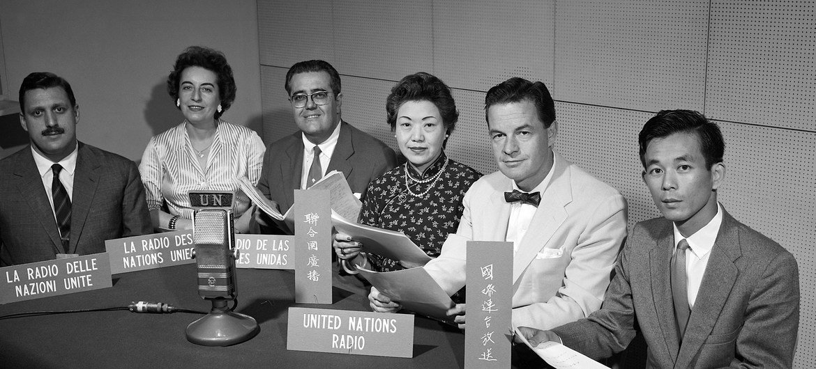 Some of the officers of the UN Radio Service in 1960 with signs indicating the languages in which they broadcast.