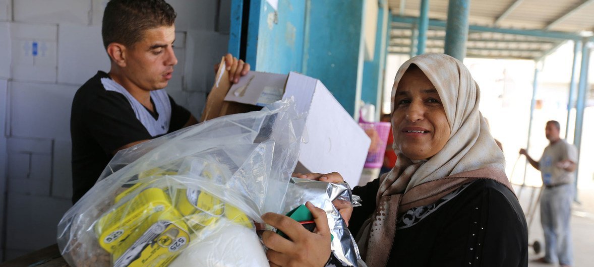 一名巴勒斯坦难民妇女在加沙的近东救济工程处汗尤尼斯分配中心领取粮食援助。