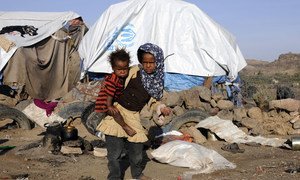 An 8-year-old girl carrying her 2-year-old brother at a settlement for persons displaced by conflict in Yemen..