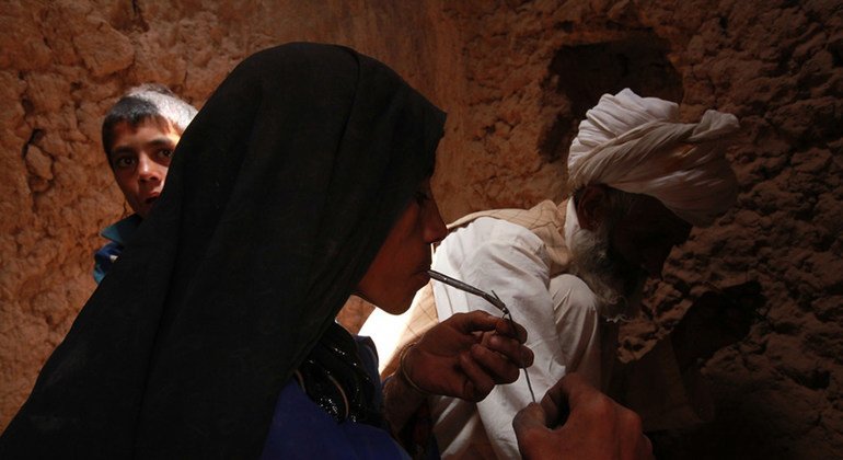 Mwanamke akivuta heroini katika pango dogo lililochimbwa na mumewe na mwanawe huko Islam Qala, Herat, Julai 2012.