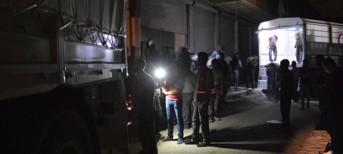 In this September 2017 photograph, humanitarians work through the night to load relief supplies onto an inter-agency convoy bound for east Ghouta, Syria.