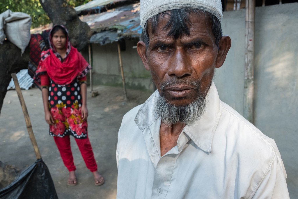 孟加拉国农民努鲁·哈克（Nurul Haque）站在他13岁的女儿前面。他说，他可能不得不让女儿辍学，嫁给一个年长的男人，因为他几乎没有别的经济选择。