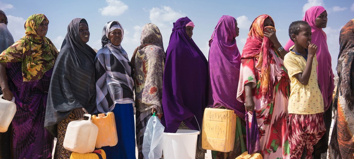 索马里流离失所的妇女拿着接水的容器排队取水。