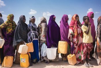 索马里流离失所的妇女拿着接水的容器排队取水。