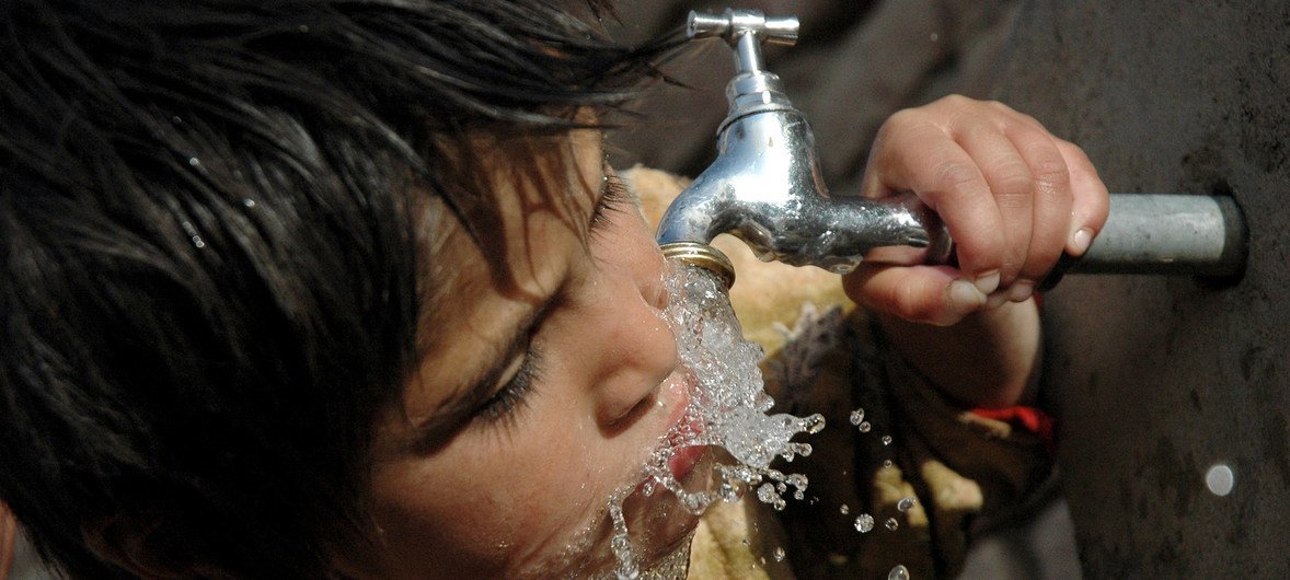 一名儿童使用水龙头饮水 。 