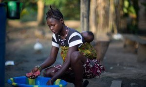 Amina Kamara, una joven de quince años, hace la colada con su hijo Ali, de seis meses, cargado a la espalda en la aldea de Motonko, en el distrito de Moyamba, en noviembre de 2015.