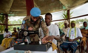 Un soldat de la paix pakistanais enseigne à un jeune libérien à coudre dans le cadre du programme offert à Tubmanburg en mai 2010.