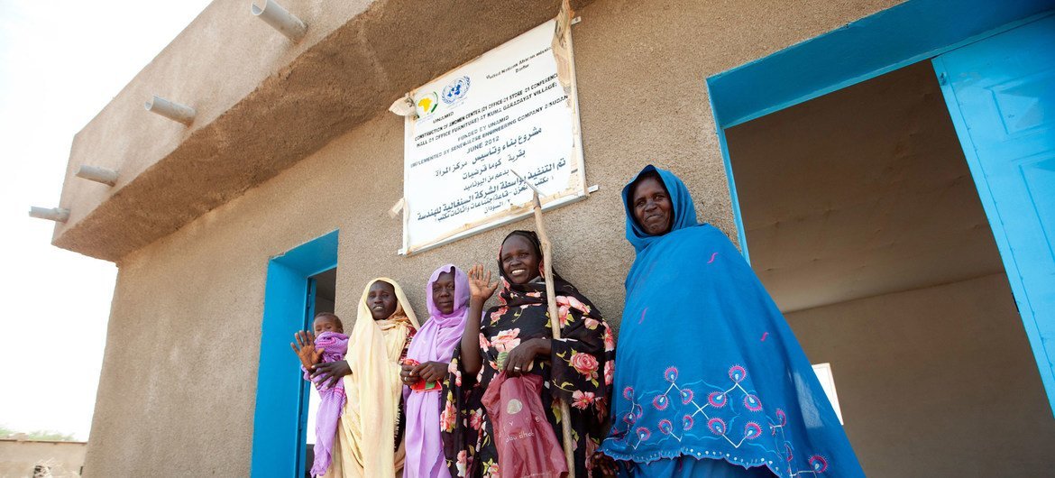 2012年，几名妇女在由非洲联盟—联合国达尔富尔混合行动修建的妇女中心门前。妇女中心是混合行动开展的六项“快速影响计划”之一，涉及教育、卫生、健康、社区发展和女性赋权等多个方面。