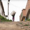 Jessica Hernández transporta sobre su espalda una de las lavadoras que alquila a los vecinos de Soacha, Colombia