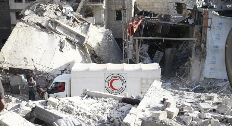Un camión del convoy de la ONU y la Media Luna Roja pasa entre los edificios destruidos de Guta, Siria.