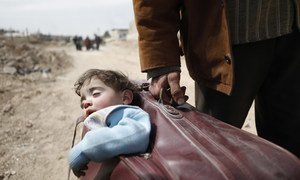 Un hombre llevando a un niño en una maleta huye de Guta Oriental hacia un refugio en Hamourieh. 