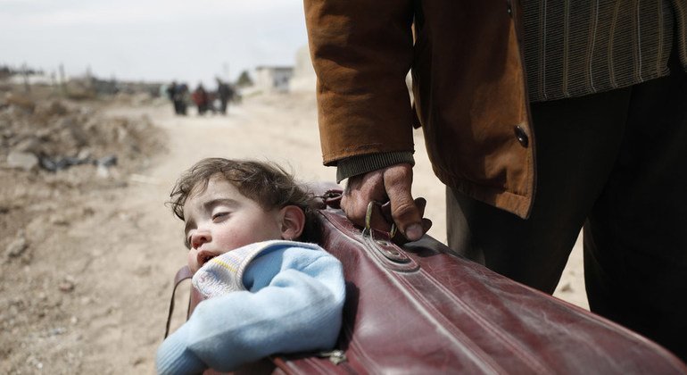 Un hombre llevando a un niño en una maleta huye de Guta Oriental hacia un refugio en Hamourieh. 