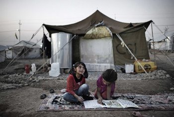 Seated on a rug atop the dirt ground, two girls complete homework outside their tent home, in the Kawergosk camp for Syrian refugees, west of Erbil, Iraq.