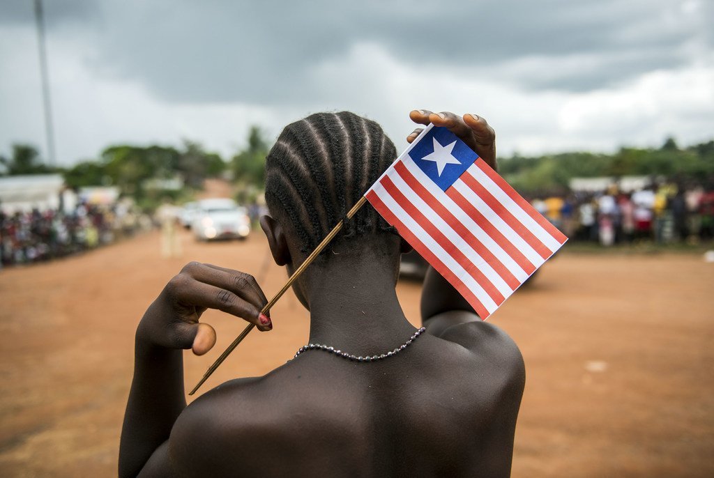 Msichana wa Liberia akiwa na bendera ya nchi yake, akionyesha utaifa wake.