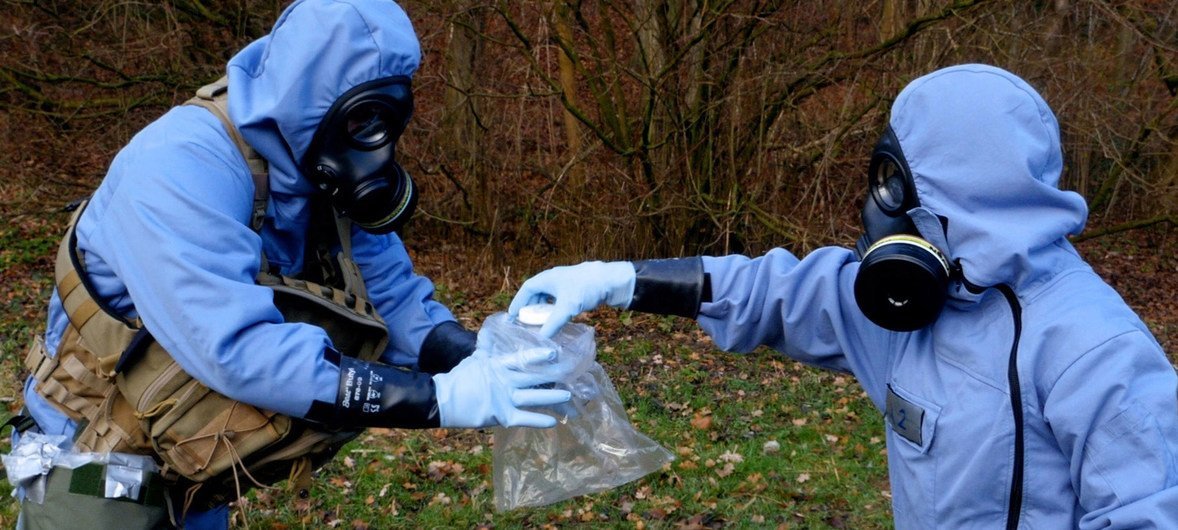 OPCW inspectors, in full protective gear, collecting samples during a mock exercise.