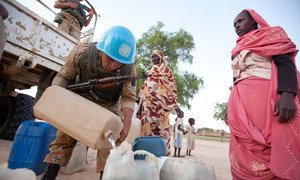 Las fuerzas de paz egipcias, junto con la Operación Híbrida de la Unión Africana y las Naciones Unidas en Darfur, distribuyen agua y harina a la población local en la localidad de Um Kadada en septiembre de 2011. 