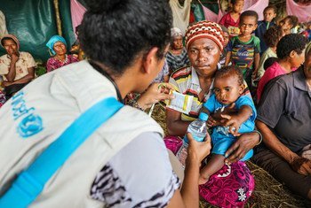 A UNICEF health official gives safe drinking water and oral retardation salts to a mother for her one-year-old child suffering from diarrhoea. They are living at temporary shelter along with at least 600 other persons after their homes were destroyed in t