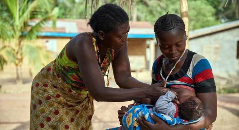 Zainab Kamara, aidée par sa mère, allaite l'un de ses deux jumeaux Alhassan Cargo, dans le village de Karineh, dans la chefferie de Magbema en Sierra Leone.