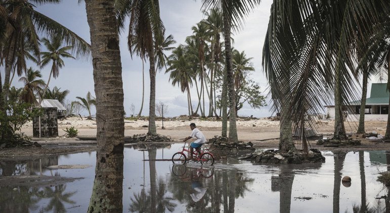 طفل يبلغ من العمر تسع سنوات يركب دراجة هوائية عبر قرية مغمورة بالمياه في جزيرة توفالو في المحيط الهادئ في أعقاب إعصار بام الذي ضرب المنطقة في عام 2015.