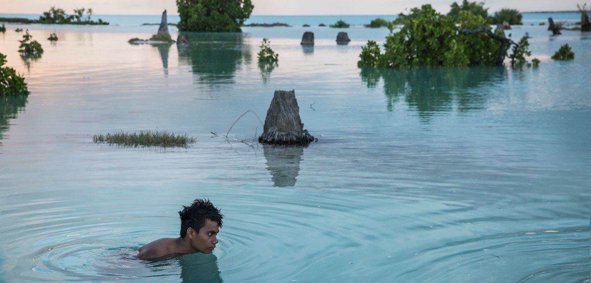 Un enfant de 16 ans nage dans la zone inondée du village d'Aberao à Kiribati. L'île du Pacifique est l'un des pays les plus touchés par l'élévation du niveau de la mer.