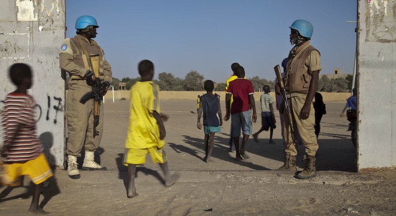 Des Casques bleus du Burkina Faso assurent la sécurité à l'entrée d'un stade avant le début du match entre les équipes de deux quartiers de Tombouctou, au Mali, en décembre 2013.