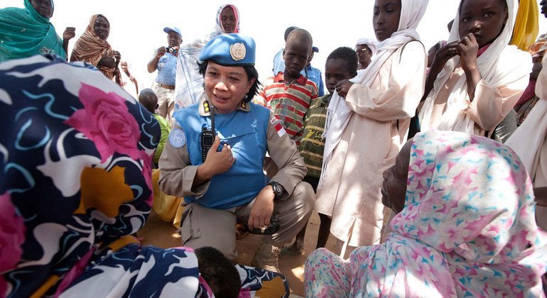 La teniente coronel Yenni Windarti, miembro de la unidad de policía indonesia en la Operación Híbrida de la Unión Africana y las Naciones Unidas en Darfur, habla con mujeres y niños en la fuente de agua del campamento para desplazadps de Abu Shouk durante