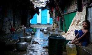 A Rohingya refugee child sits next to buckets collecting rainwater at a makeshift refugee camp in Cox's Bazar, Bangladesh. With the arrival of rains, the challenges have multiplied for hundreds of thousands of refugees in the area.