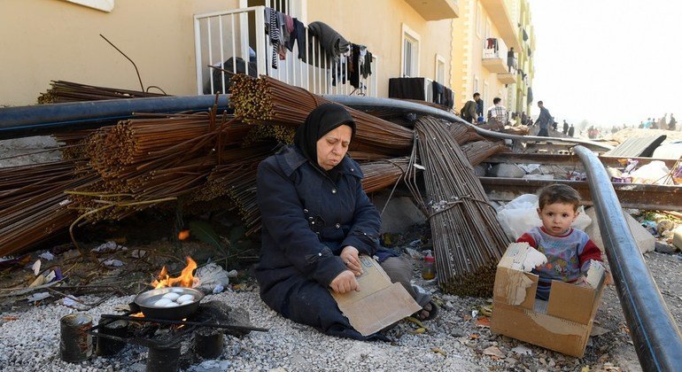 Una madre y su niño que huyeron de los combates en Guta Oriental usan cartones para hervir unos huevos en el albergue de Herjelleh a las afueras de Damasco.