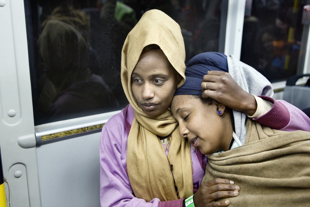 لاجئة من إريتريا تحتضن صديقتها في حافلة نقل في المطار. اللاجئتان من بين 162 لاجئا كانوا معرضين للخطر، حيث تم إجلاؤهم مباشرة من ليبيا إلى إيطاليا في أواخر ديسمبر 2017.