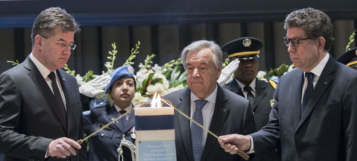 Le Secrétaire général de l'ONU, Antonio Guterres, au centre, allume une bougie lors d'une cérémonie en hommage aux employés de l'ONU décédés dans l'exercice de leurs fonctions.