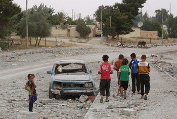في الصورة طفل سوري  يسير بصحبة أصدقائه بجوار سيارة مدمرة.  وقد نزح مع عائلته مرتين خلال سنوات القتال وأجبر على ترك الدراسة. مدينة الطبقة - سوريا