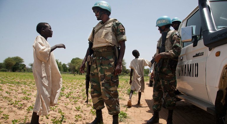 Dos niños se ven aquí hablando con un miembro de la paz de UNAMID que es de Etiopía en el área volátil de Gereida en el sur de Darfur en julio de 2012.  