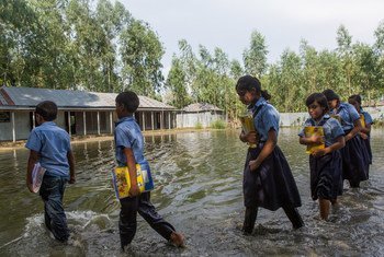 孟加拉国每年都会发洪水，图为2014年9月9日发生洪灾后，学生们上学的路上。2020年季风季节，该国的洪水异常严重。